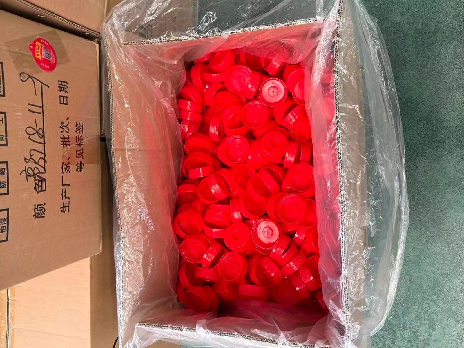 Export carton with a sealed polythene liner being filled with red bottle caps